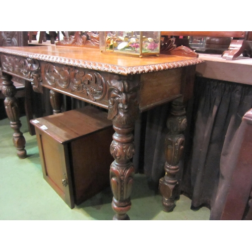 4202 - A carved oak 'Green Man' style side table, 91cm tall x 113cm wide x 43cm deep