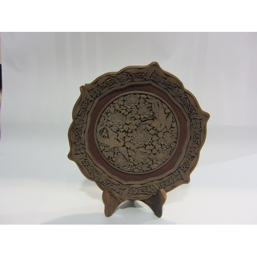 4008 - An intricately carved Oriental hardwood dish inset with cinnabar lacquer and decorated with birds am... 