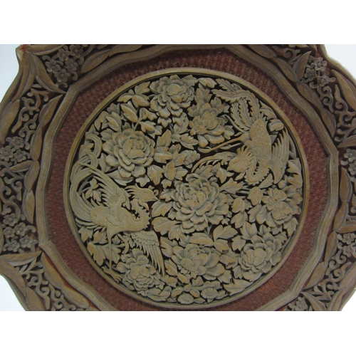 4008 - An intricately carved Oriental hardwood dish inset with cinnabar lacquer and decorated with birds am... 