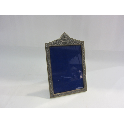 4461 - A Thai white metal photograph frame with allover repousse design and deity to top, 18cm x 12.5cm ape... 