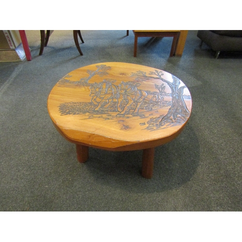 1159 - An elm occasional table with carved decoration of farmer and heavy horses ploughing a field, 37cm ta... 