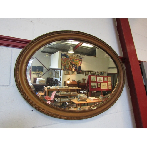 1310 - A gilt framed oval wall mirror, bevel edged, beading missing, 60cm x 85cm total