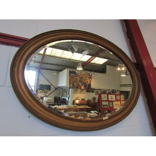 1310 - A gilt framed oval wall mirror, bevel edged, beading missing, 60cm x 85cm total