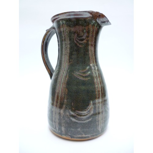 1317 - A tall Winchcombe studio pottery stoneware jug. Tenmoku glaze and finger wipe detail. Seal under str... 