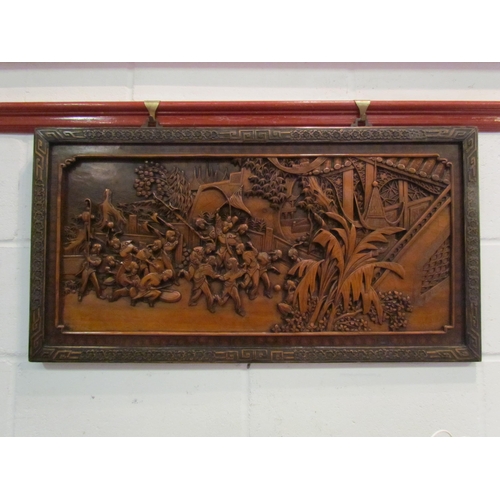 1340 - An early 20th Century Oriental carved panel depicting celebratory scenes, 45cm x 86cm