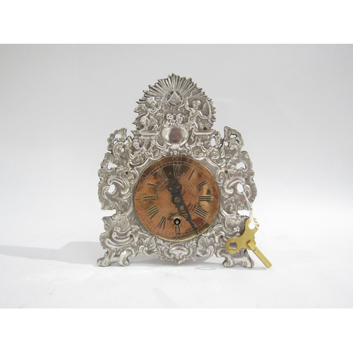 8059 - A German mantel timepiece, baroque style repousse silver plated front with brass dial 3.5