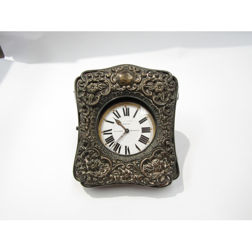 8115 - An embossed silver travelling clock case together with a Finnigans of Manchester 8 day clock