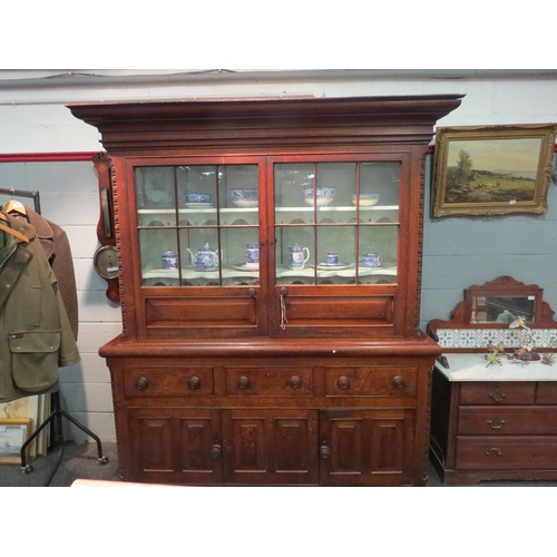 1075 - An early 20thC oak dresser, two door astral glazed and panelled top over three short drawers and thr... 