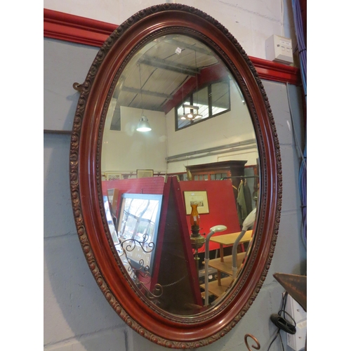 1101 - An oval bevel edged mirror, 87cm x 62cm total