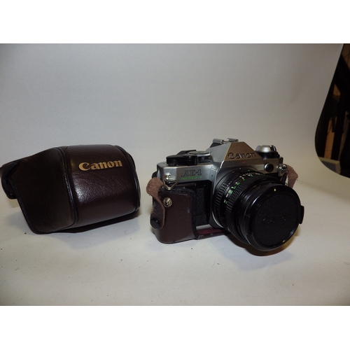 5013 - A Canon AE1 Program SLR camera with 50mm lens, a Canon AT-1 SLR camera with 50mm lens and a Canon QL... 