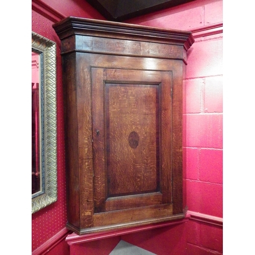 4113 - A George III oak and burr walnut single door wall hanging corner cupboard with key and painted inter... 