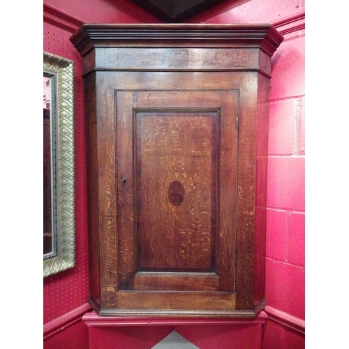 4113 - A George III oak and burr walnut single door wall hanging corner cupboard with key and painted inter... 