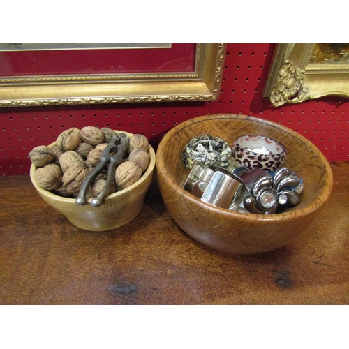 4077 - A turned wood Scottish bowl containing nuts and nutcrackers together with an oak bowl containing bij... 