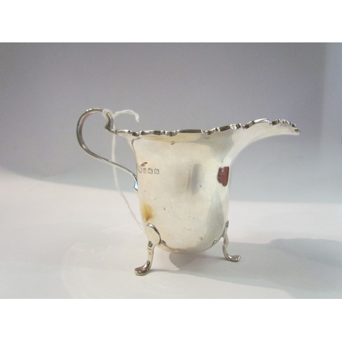 4330 - An Alexander Clark and Co Ltd silver cream jug on three legs, Birmingham 1928, 57g