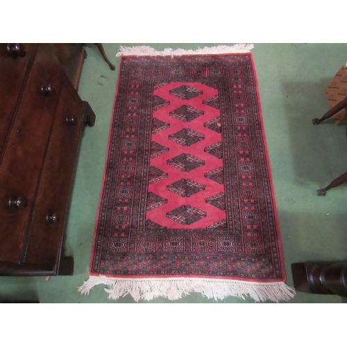 4106 - A Pakistan wool rug, dark pink ground with green and white motif, multiple borders, tasselled ends, ... 