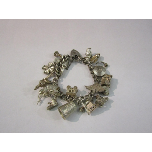 4421 - A silver charm bracelet hung with various charms including scarecrow, church, beer bottle etc, 79g