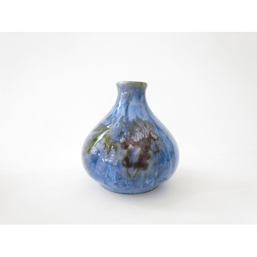 7524 - A Cobridge Stoneware onion shaped vase in mottled blue glaze with bunches of grapes and vine leaf de... 