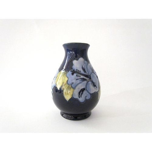 7558 - A Moorcroft Hibiscus pattern vase in pale blue with dark blue ground, 14cm tall