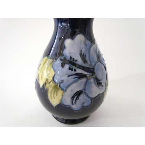 7558 - A Moorcroft Hibiscus pattern vase in pale blue with dark blue ground, 14cm tall