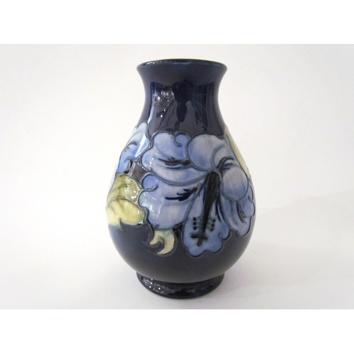 7558 - A Moorcroft Hibiscus pattern vase in pale blue with dark blue ground, 14cm tall