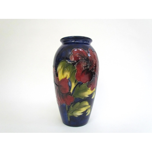 7562 - A Moorcroft Hibiscus pattern vase, deep red on a dark blue ground, 18.5cm tall