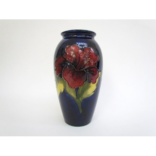 7562 - A Moorcroft Hibiscus pattern vase, deep red on a dark blue ground, 18.5cm tall