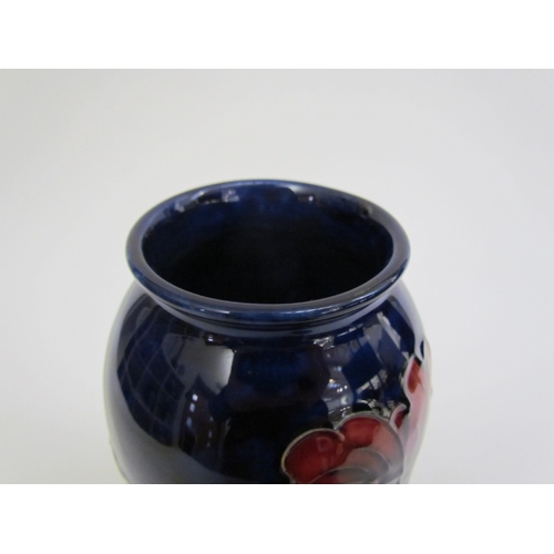 7562 - A Moorcroft Hibiscus pattern vase, deep red on a dark blue ground, 18.5cm tall