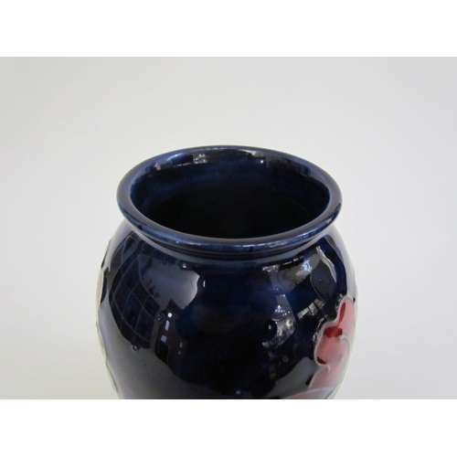 7562 - A Moorcroft Hibiscus pattern vase, deep red on a dark blue ground, 18.5cm tall