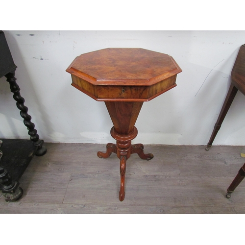 7606 - A reproduction burr walnut sewing table, the octagonal top over a faceted column to a carved tripod ... 