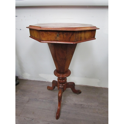 7606 - A reproduction burr walnut sewing table, the octagonal top over a faceted column to a carved tripod ... 