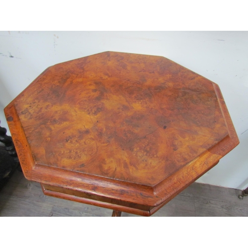 7606 - A reproduction burr walnut sewing table, the octagonal top over a faceted column to a carved tripod ... 