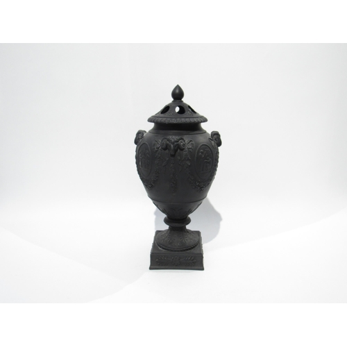 7189 - A Wedgwood black basalt lidded urn with ram's head detail. The lid is damaged and nibble to rim, 32c... 