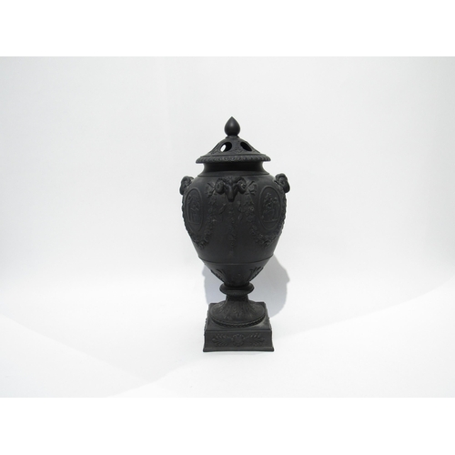 7189 - A Wedgwood black basalt lidded urn with ram's head detail. The lid is damaged and nibble to rim, 32c... 