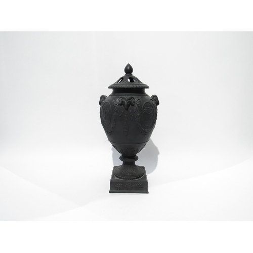 7189 - A Wedgwood black basalt lidded urn with ram's head detail. The lid is damaged and nibble to rim, 32c... 