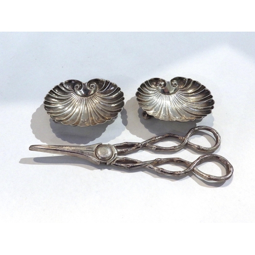 7208 - A pair of silver grape scissors with branch effect handles and two white metal scallop form dishes, ... 