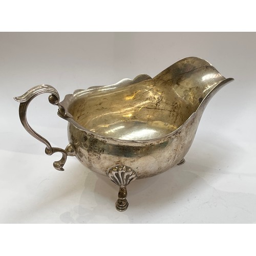 7316 - An Elkington & Co. silver gravy boat, scroll handle, shell and hoof feet, shaped edge, Birmingham 19... 