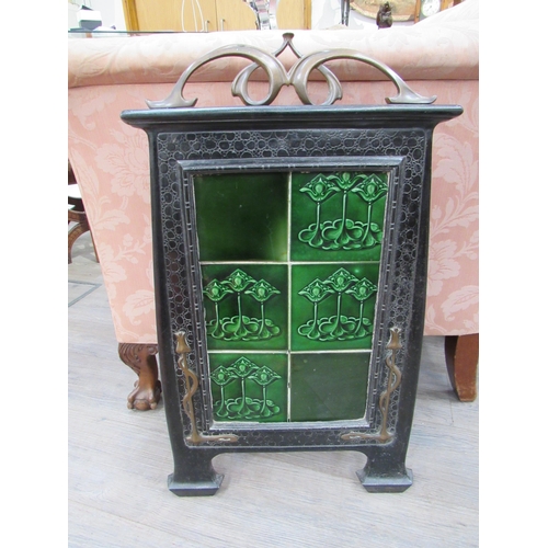 7823 - An Art Nouveau fire screen, the scrolled brass top over a black metal frame, green tiled centre, 76c... 