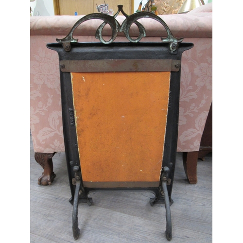 7823 - An Art Nouveau fire screen, the scrolled brass top over a black metal frame, green tiled centre, 76c... 