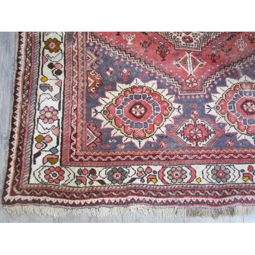 7643 - A Middle Eastern wool rug, central lozenge, dark pink ground, multiple borders, 143cm x 128cm