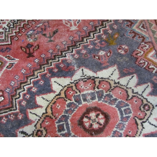 7643 - A Middle Eastern wool rug, central lozenge, dark pink ground, multiple borders, 143cm x 128cm