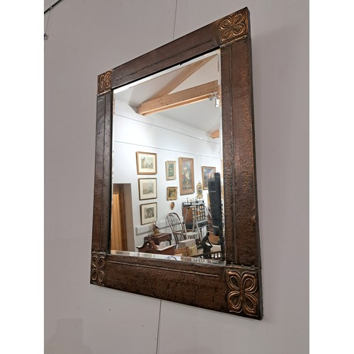 7582A - An Arts and Crafts hammered copper wall mirror of rectangular form, Celtic style corners