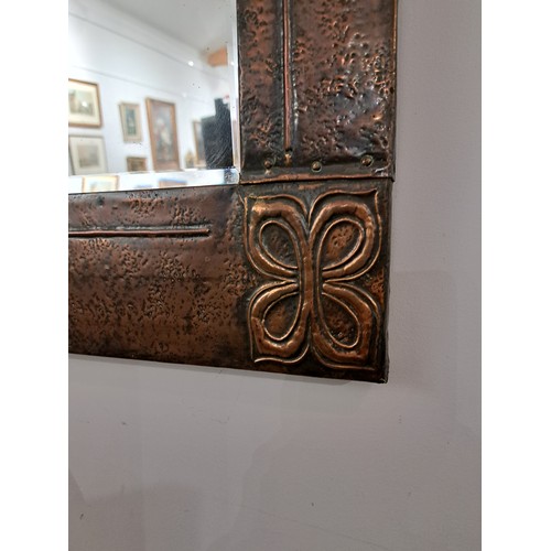 7582A - An Arts and Crafts hammered copper wall mirror of rectangular form, Celtic style corners