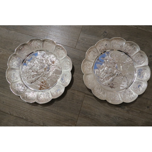 7471A - A pair of white metal scalloped form chargers with centres depicting Japanese warriors, 31cm diamete... 