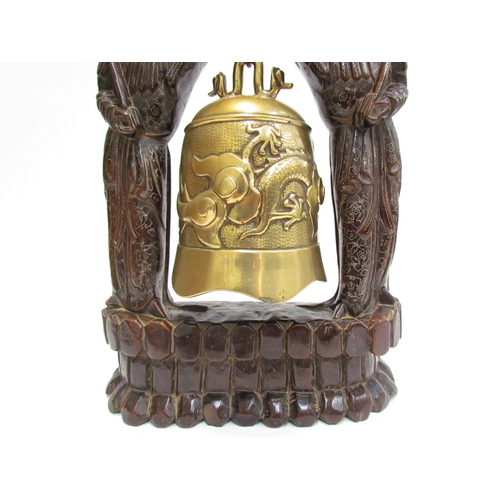 7602 - An Oriental carved hardwood and brass bell, 45cm high