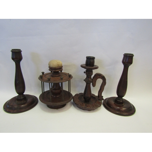 1231 - A turned hardwood thread dispenser with pin cushion, a pair of candlesticks and carved chamber stick... 