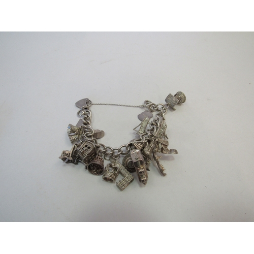 1414 - A silver charm bracelet hung with multiple charms including wishing well, London bridge, train, Big ... 