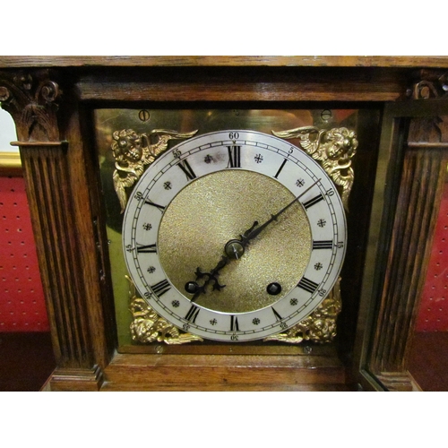 4027 - An oak cased mantel clock with engraved column design to case, cherubs to corners of face. Roman num... 