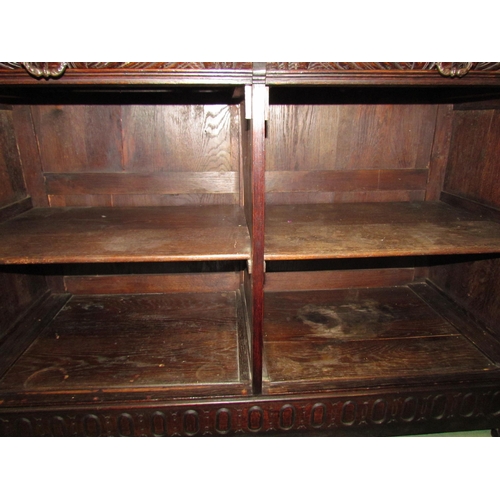 4048 - A late Victorian carved oak sideboard with lion's head and winged angel decoration, the two drawers ... 