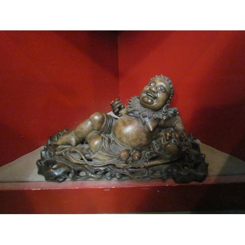 4111 - An Eastern carved wooden Budai laying beside dragon on fitted base, 40cm long