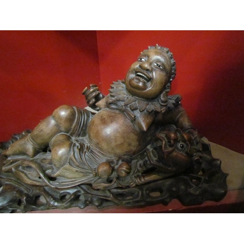 4111 - An Eastern carved wooden Budai laying beside dragon on fitted base, 40cm long